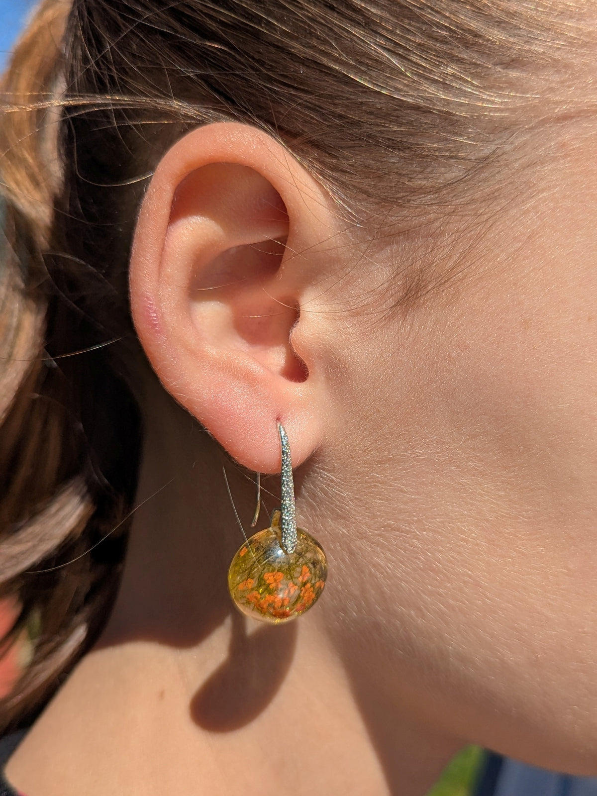 Close-up of real pressed flowers and forest moss inside clear resin earrings, EL Creations