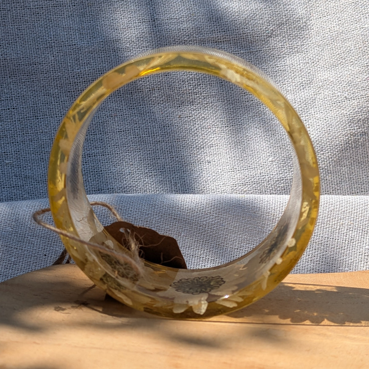 Transparent resin bangle showcasing white daisies and golden centers by EL-Creations