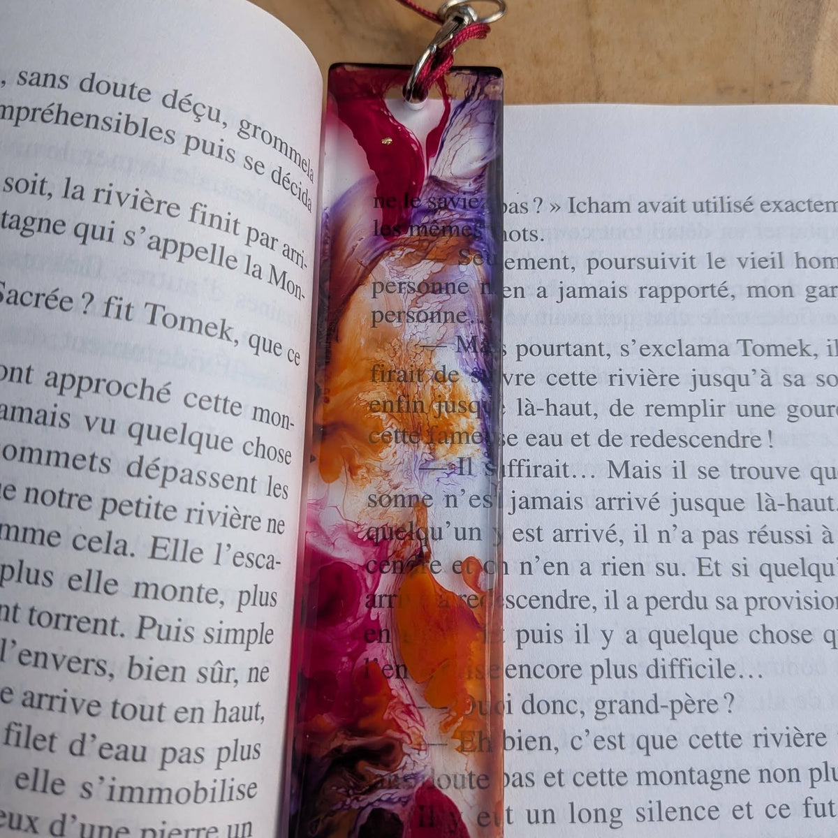 Top angle view of crimson raspberry purple resin bookmark lying across open book – EL-Creations
