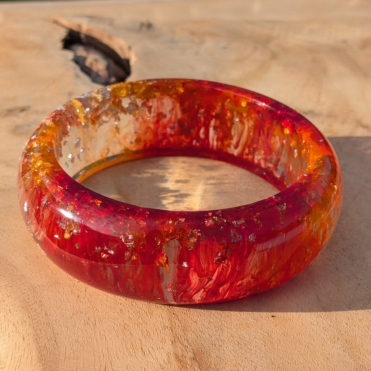 Wide red and orange resin bangle with silver gold leaf on wooden background – EL-Creations