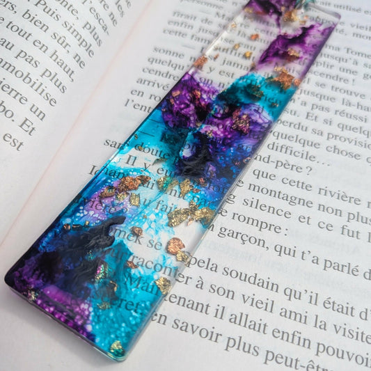 Full length cosmic tide resin bookmark diagonal across open book with teal tassel – EL-Creations