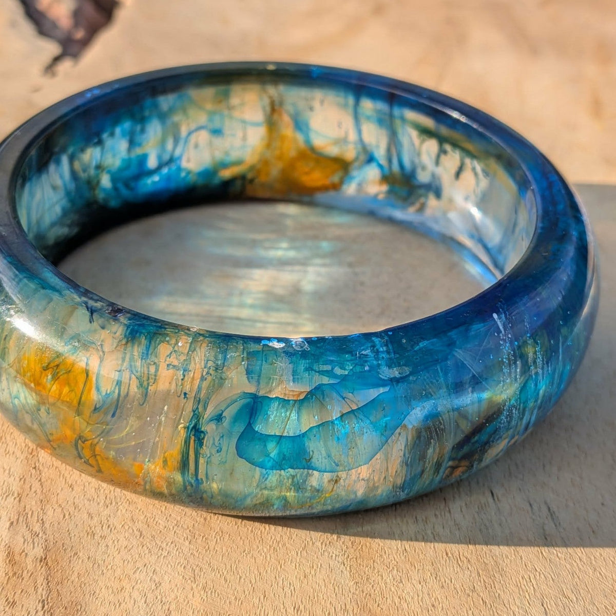 Close-up of deep blue and teal resin bangle surface with gold shimmer detail – EL-Creations