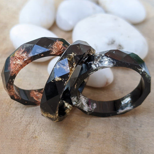 Black faceted resin ring for men and women - top view on wood