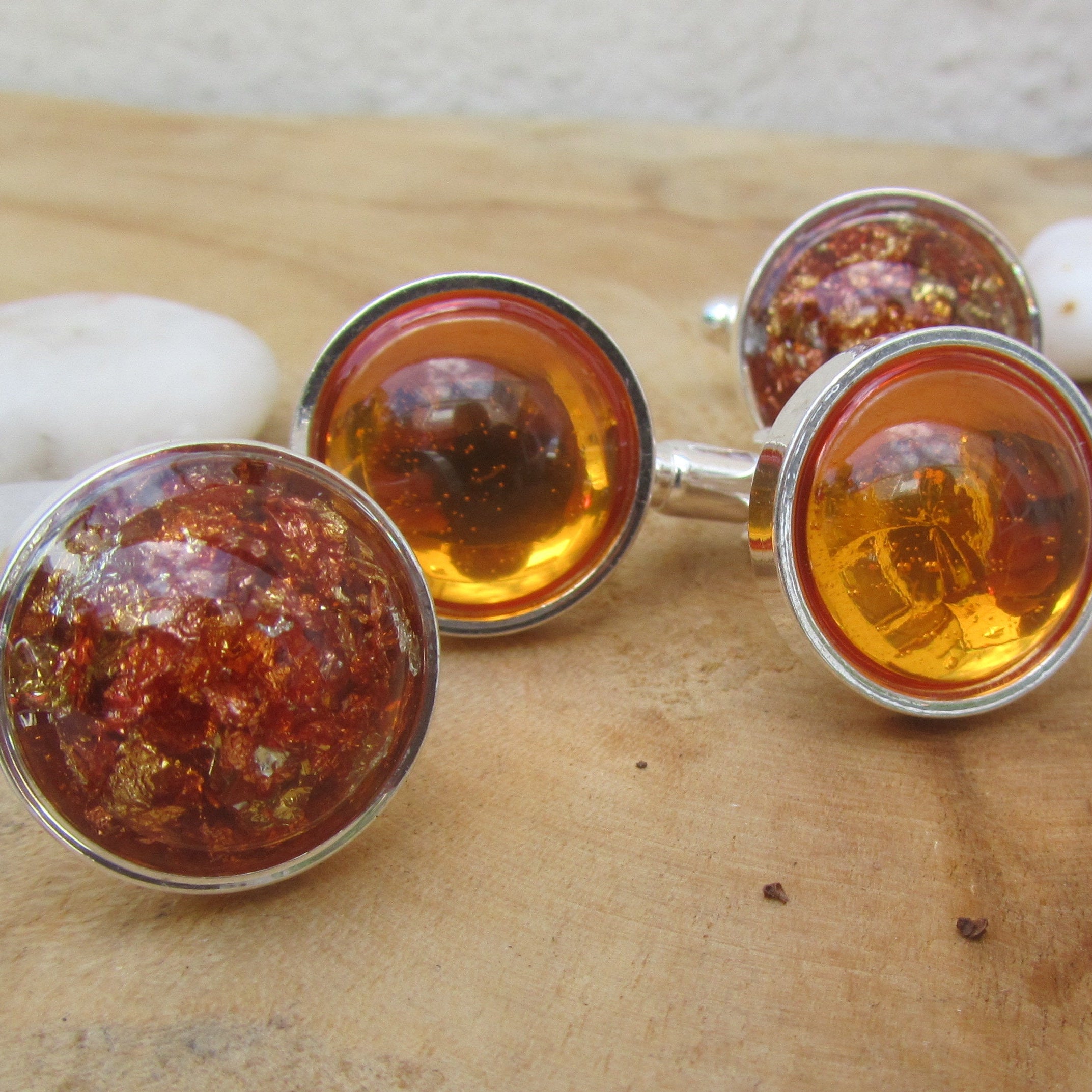 Cufflinks with amber-colored stones on a wooden surface