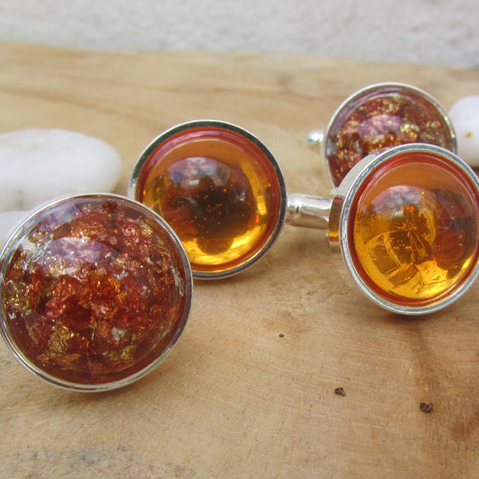 Cufflinks with amber-colored stones on a wooden surface