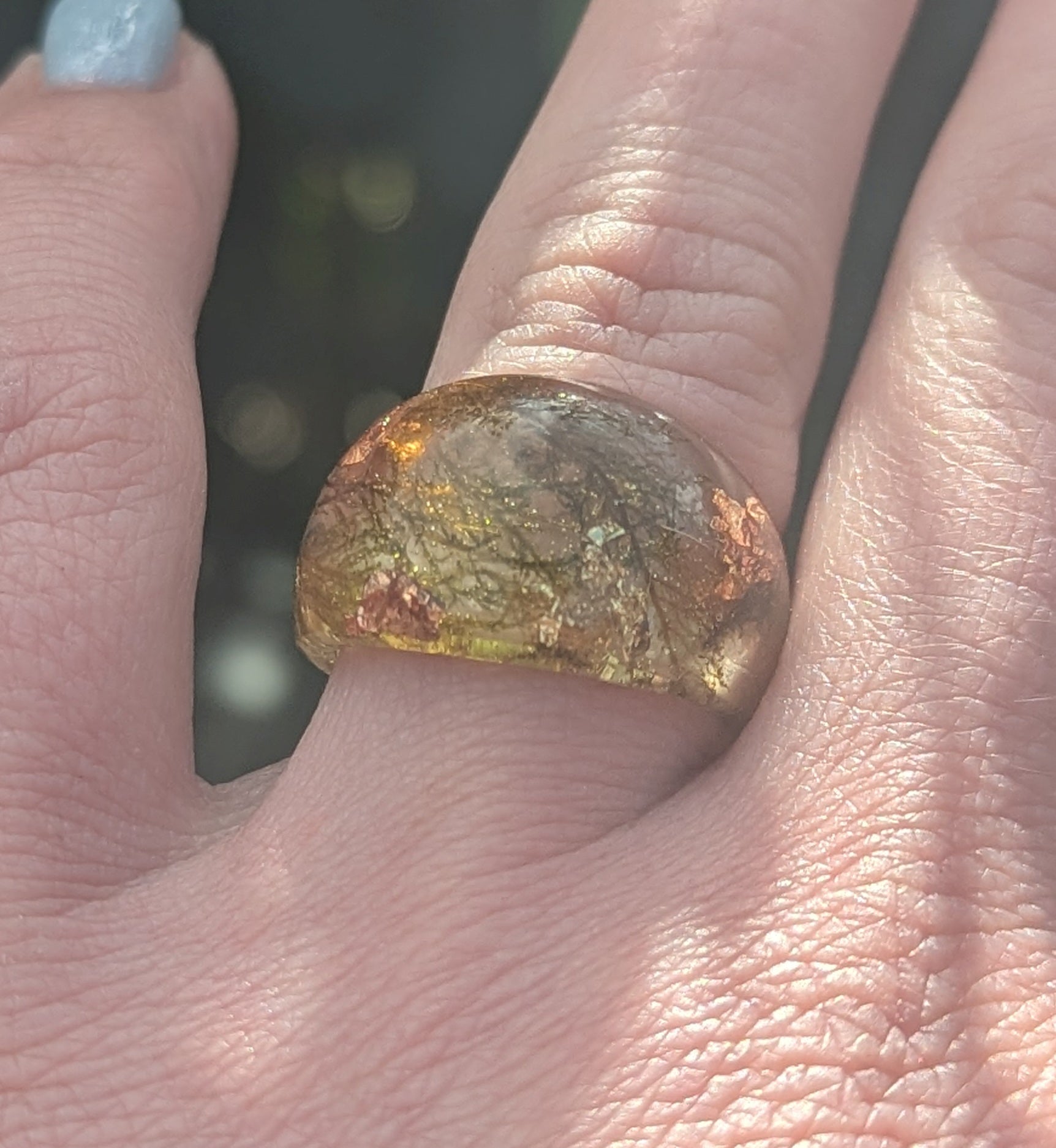 Close-up of a hand wearing a ring with a large, faceted gemstone.