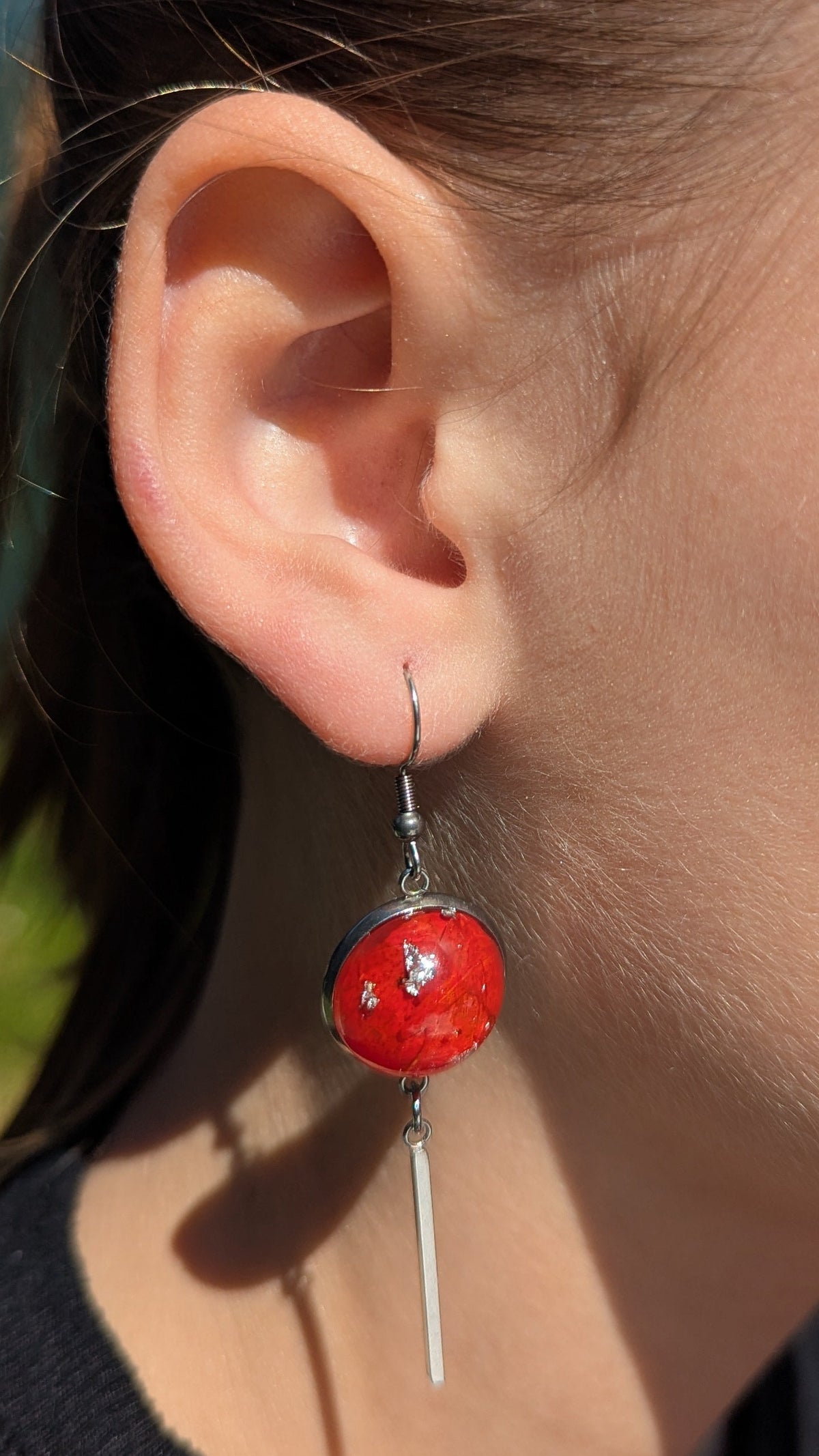 Red pressed leaf resin bar earrings worn on ear, nature-inspired statement jewelry EL Creations Belgium
