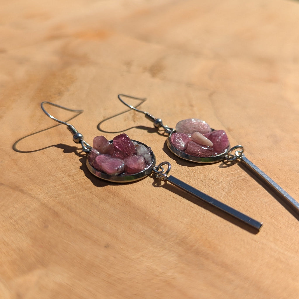 Pair of earrings with pink stones on a wooden surface