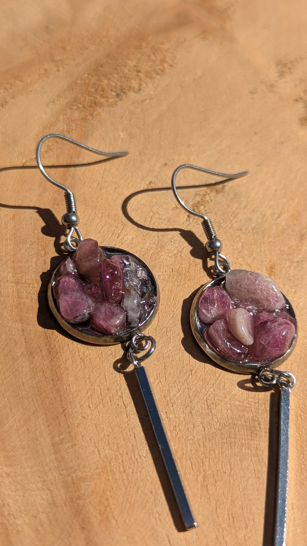 Pair of earrings with purple stones on a wooden surface