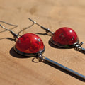 Red earrings with silver hooks on a wooden surface