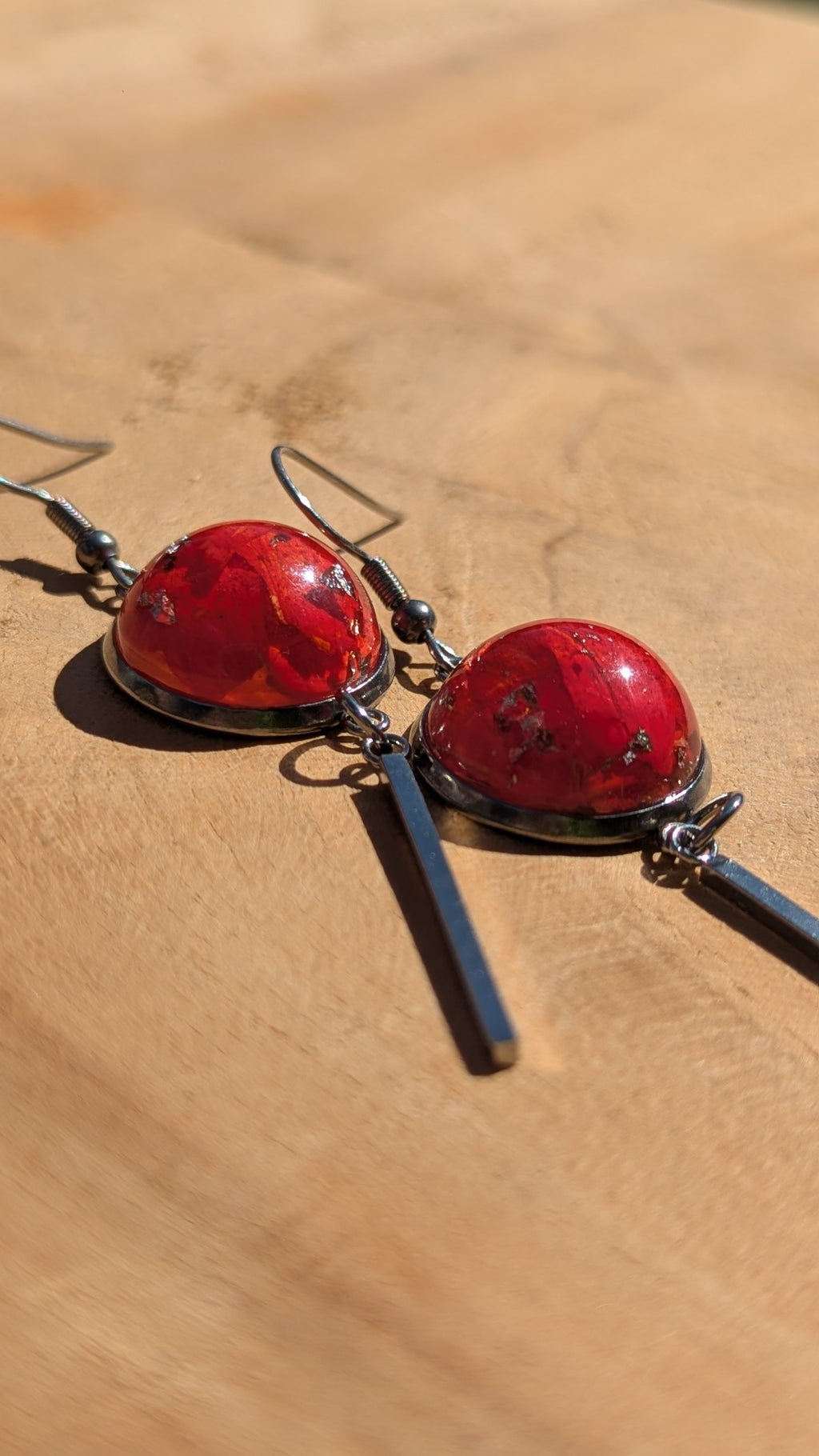 Red earrings on a wooden surface
