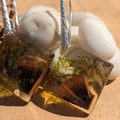 Pair of earrings with embedded stones on a wooden surface