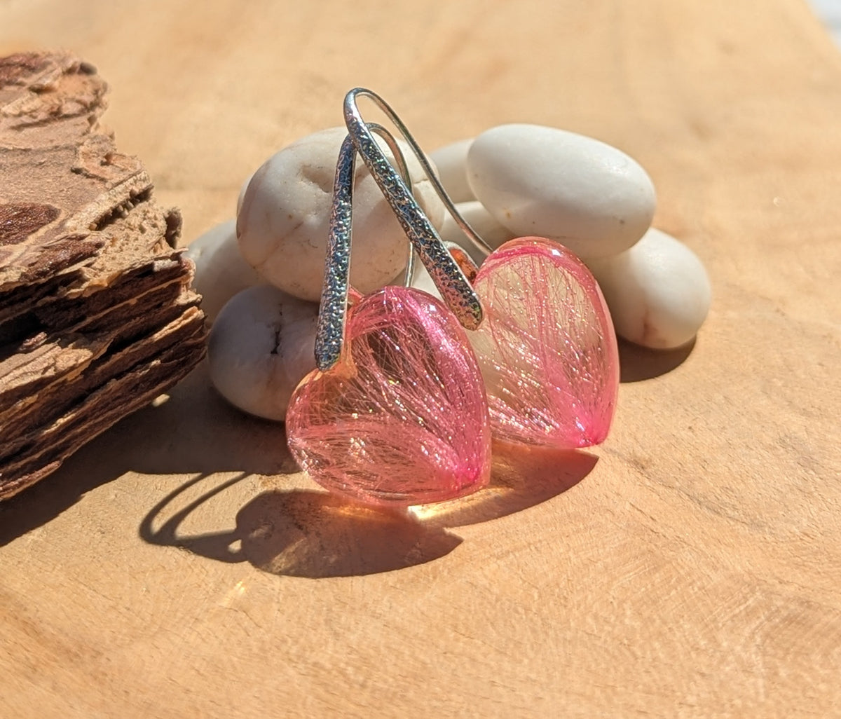 Close-up of real pink pressed flowers inside heart-shaped resin earrings, EL Creations