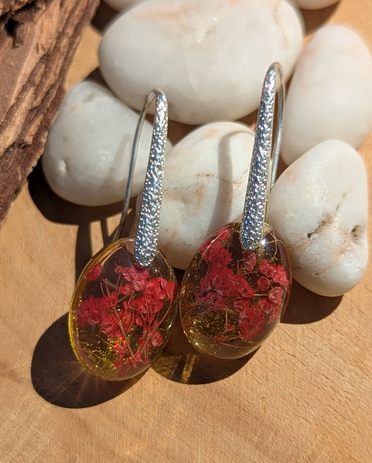 Close-up of real red flowers and moss inside clear oval resin earrings, EL Creations Belgium
