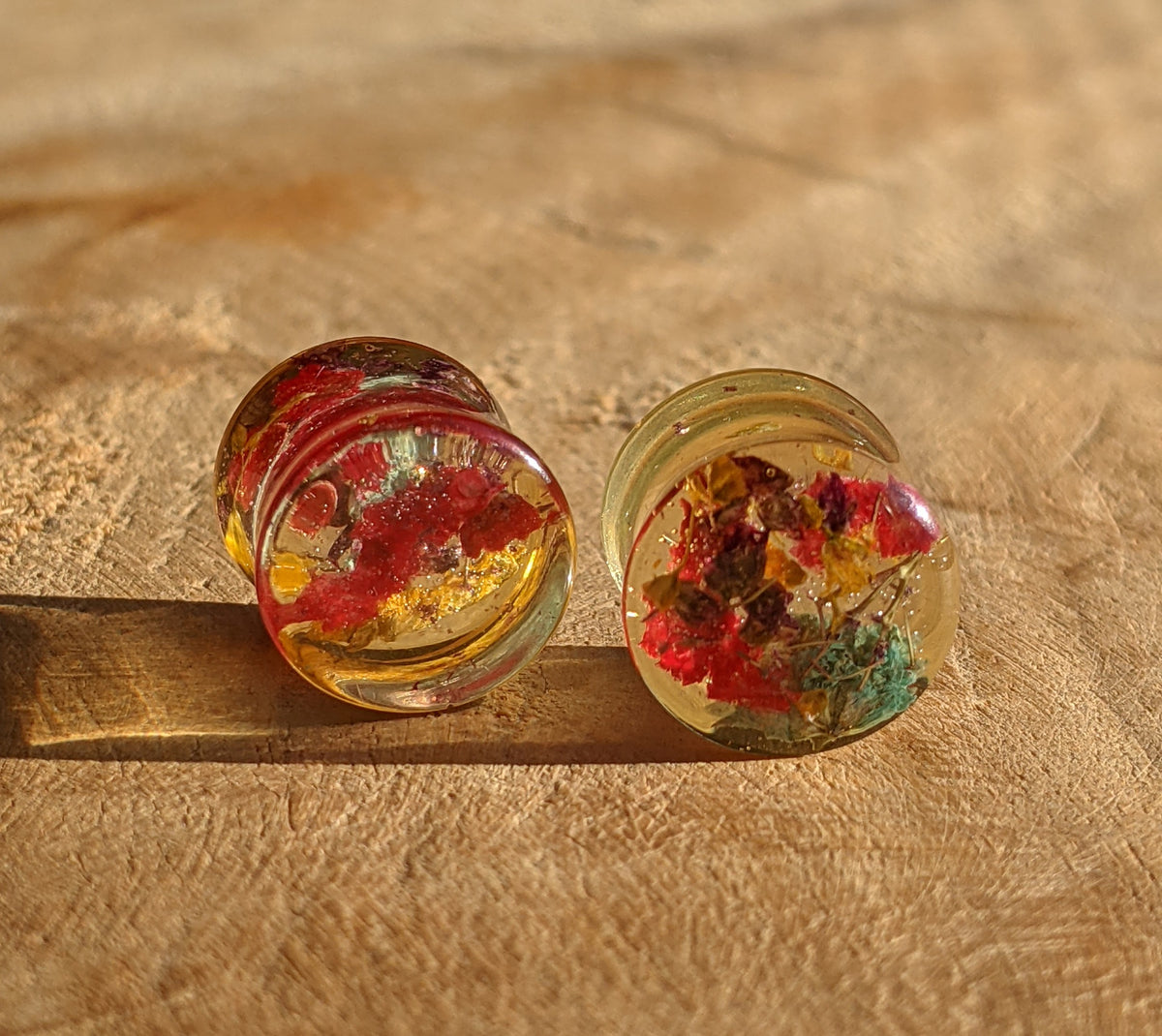 Close up of multicolor dried flowers preserved in resin ear plugs EL-Creations