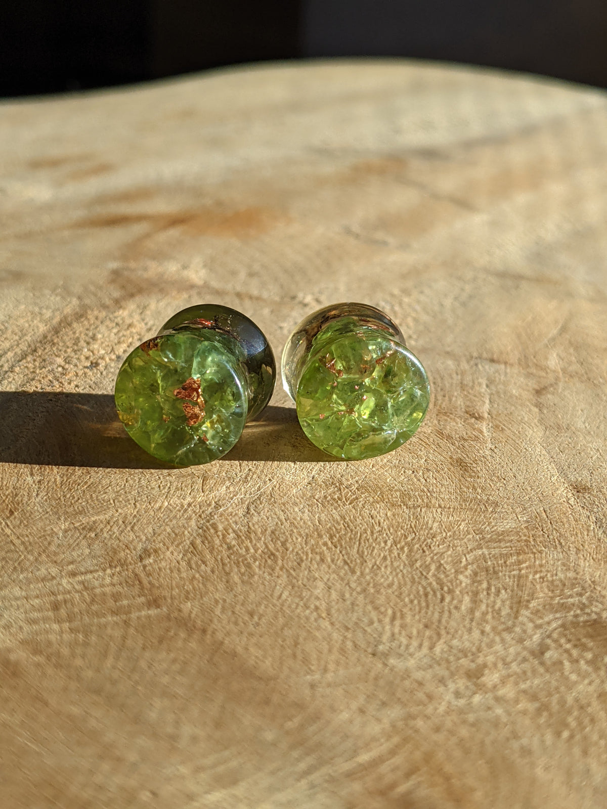 Green resin ear plugs with peridot gemstones
