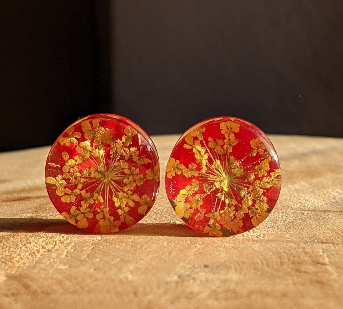 Close up of yellow flower petals and tulip leaf preserved in resin ear plugs EL-Creations