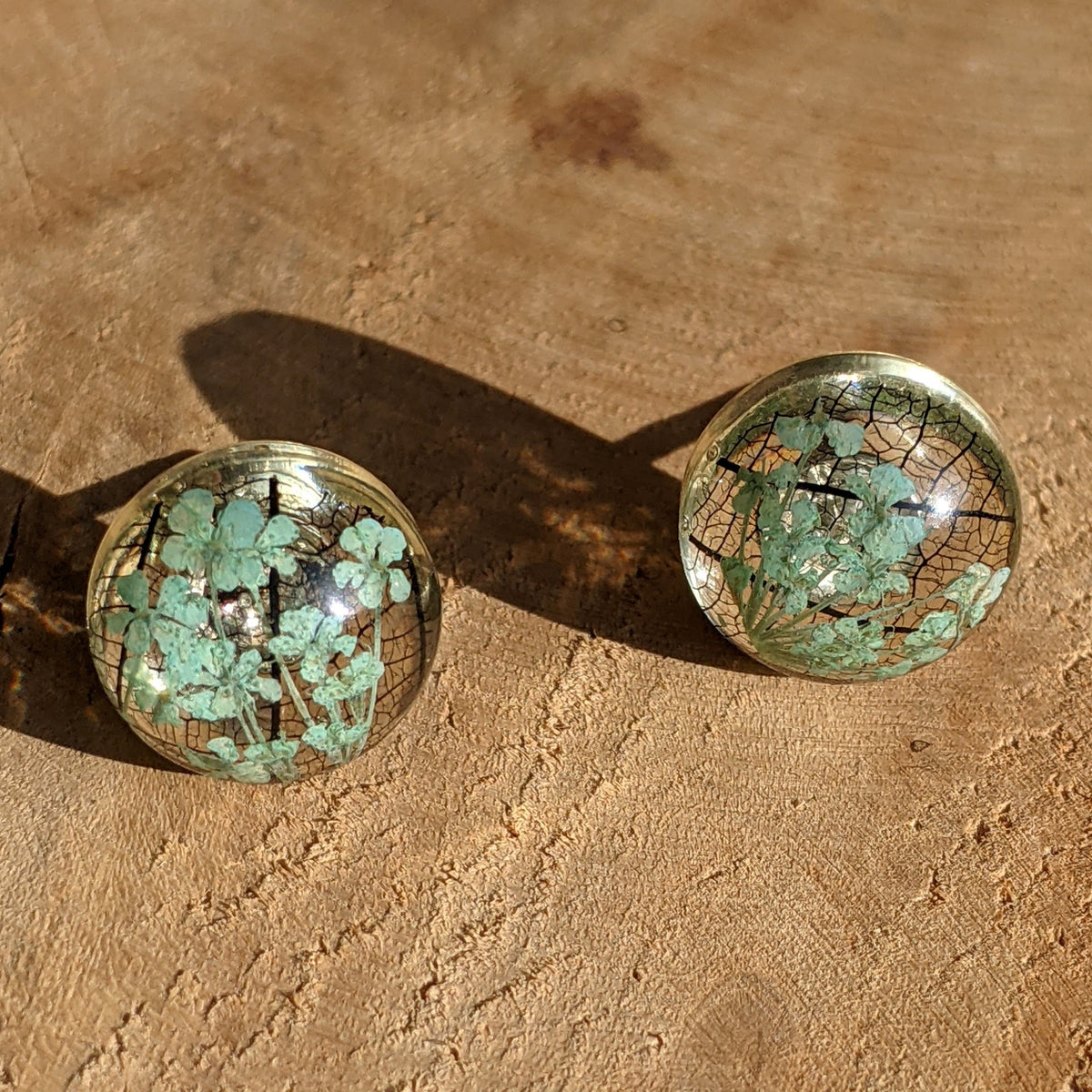 Handmade resin stud earrings with turquoise flower and black skeleton leaf, silver-toned base, EL Creations Belgium