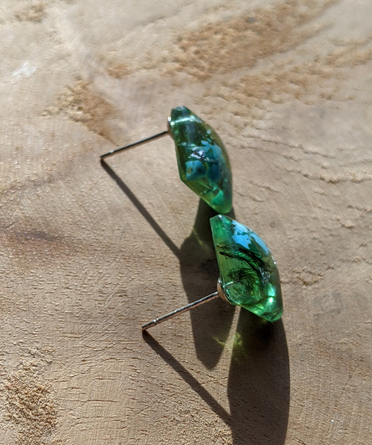 Close-up of turquoise stone moss and silver flakes inside clear resin square stud earrings, EL Creations