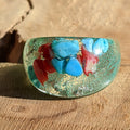 Colorful glass bead with red and blue stones on a wooden surface