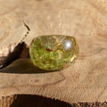 Green gemstone ring on a wooden surface