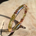 Bangle with embedded natural elements on a stone surface