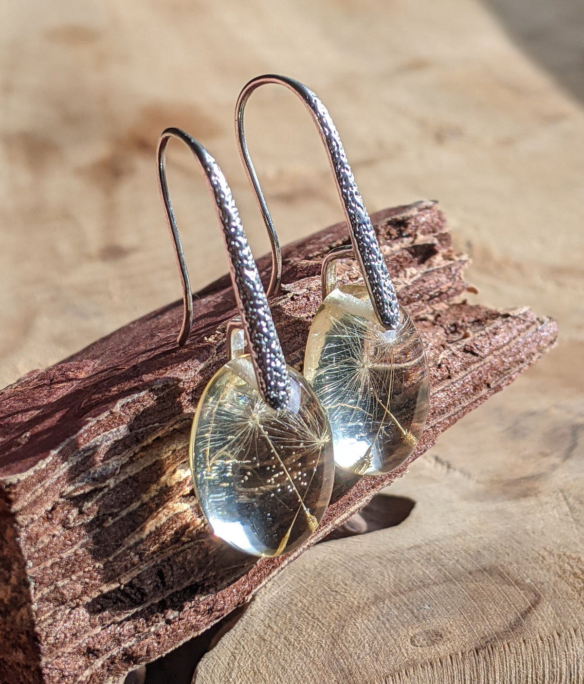 Sterling silver dandelion seed resin earrings on wooden surface, EL Creations