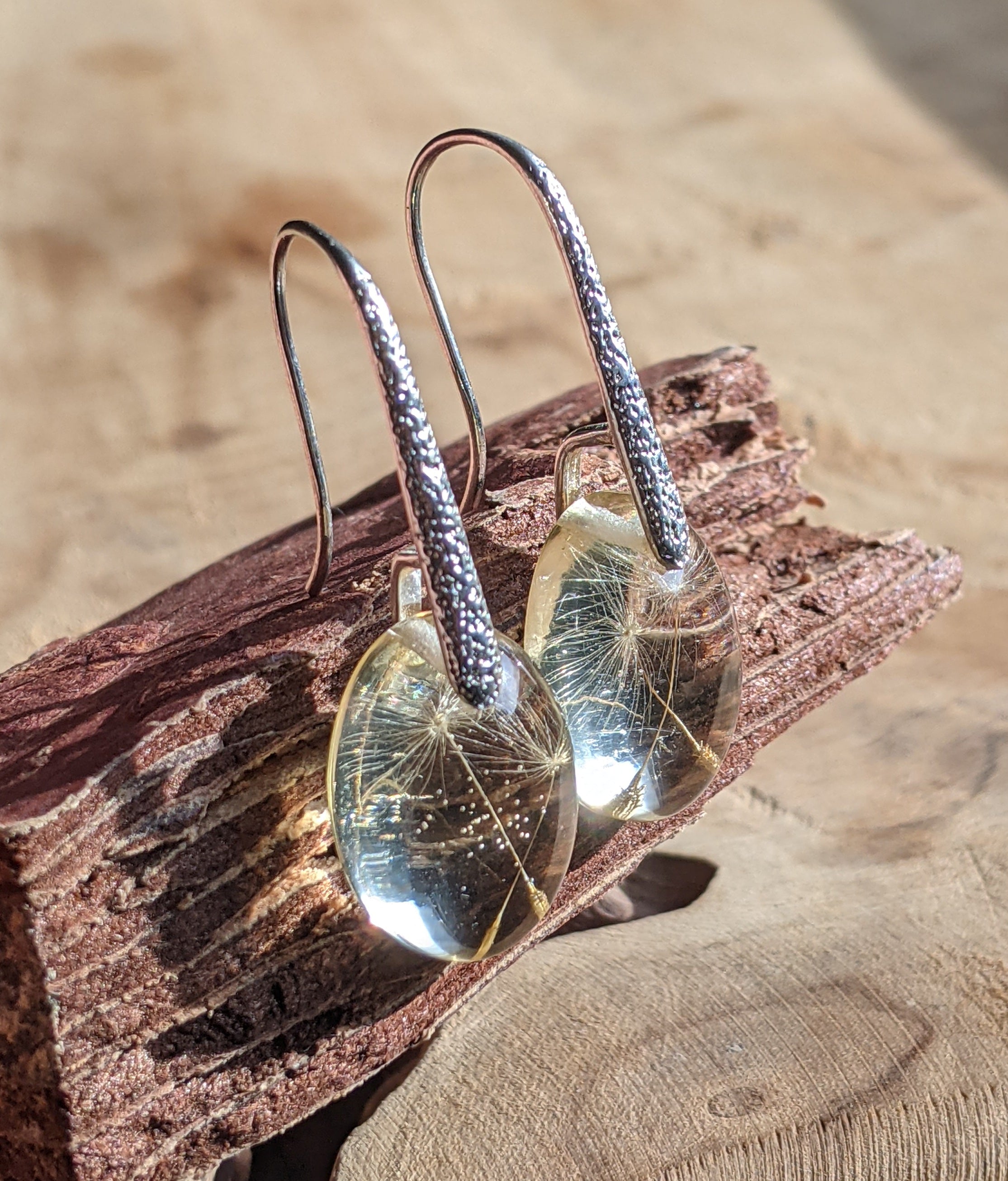 Silver earrings with clear resin on a wooden surface