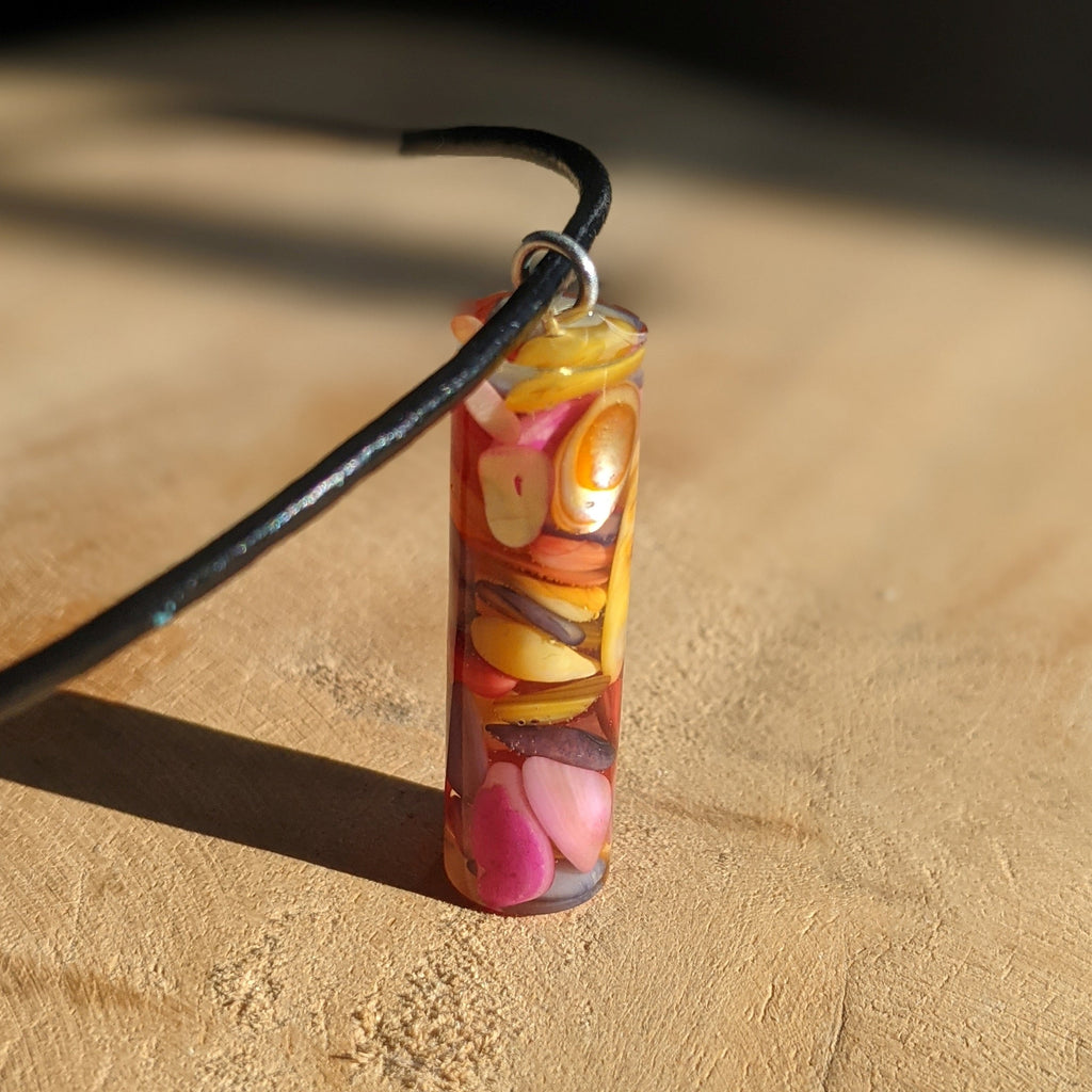 Colorful pendant on a black cord against a wooden background