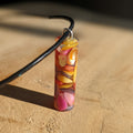 Colorful pendant on a black cord against a wooden background