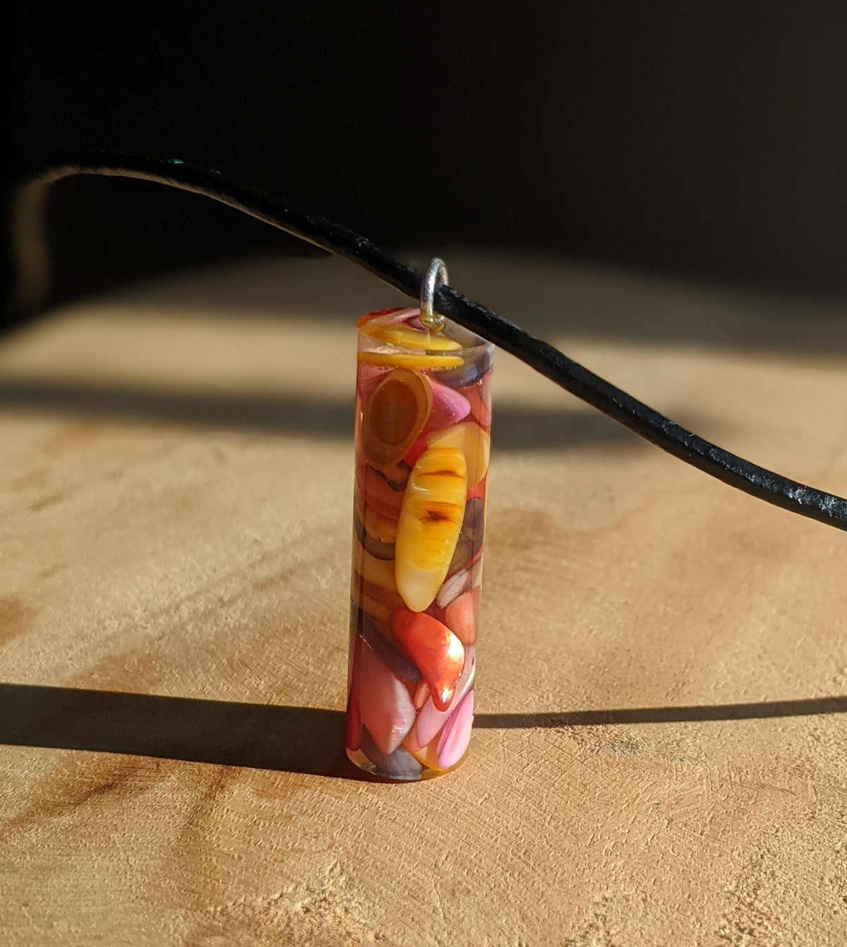 Close up view of colorful stones preserved inside clear resin necklace pendant EL-Creations