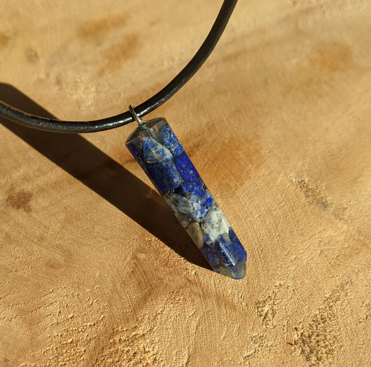 Close up view of lapis lazuli stones preserved inside crystal point resin pendant EL-Creations