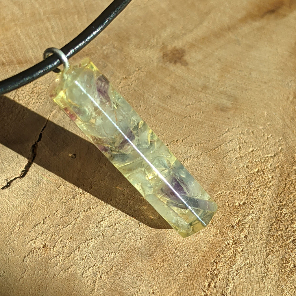 Crystal pendant on a black cord against a beige background