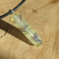 Crystal pendant on a black cord against a beige background