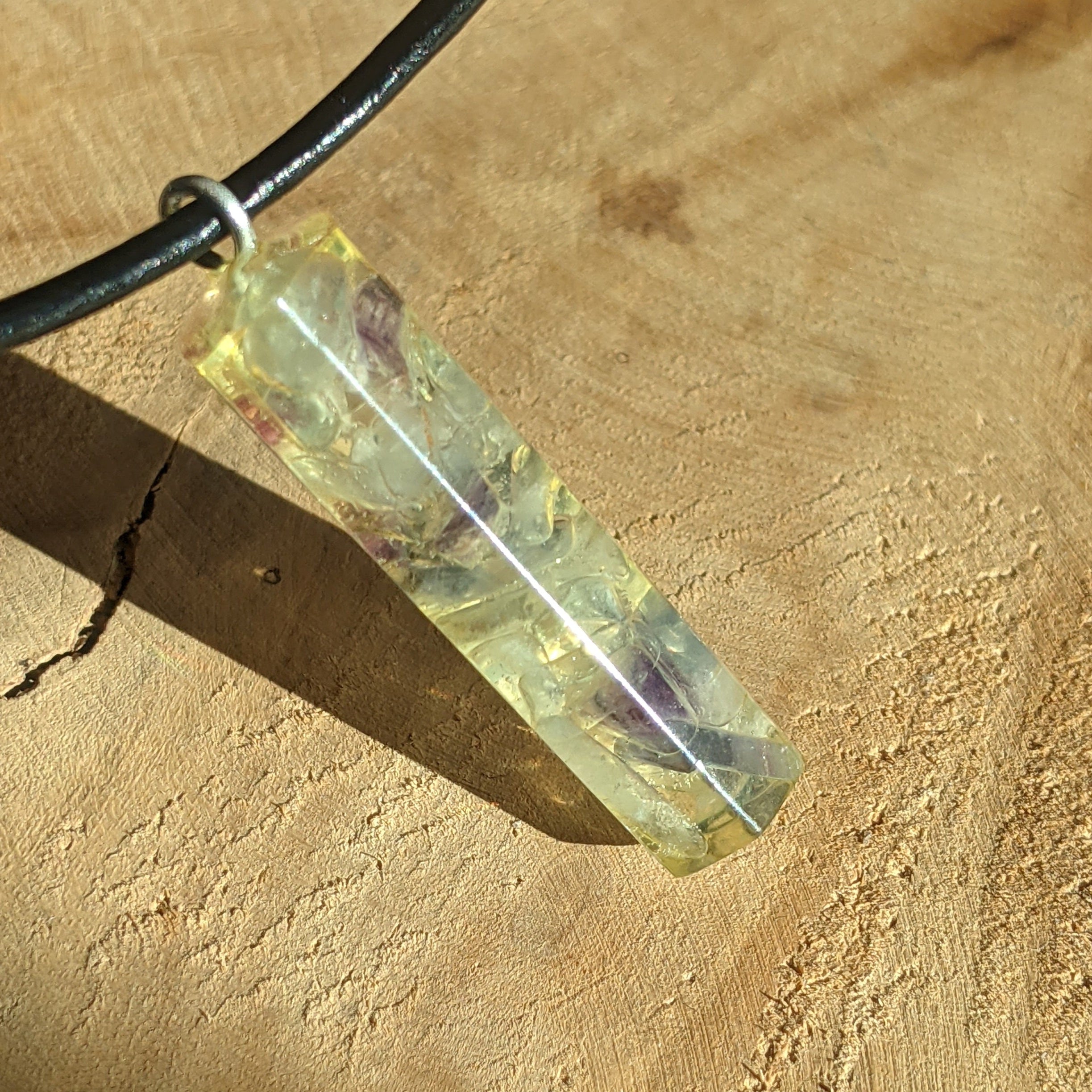 Crystal pendant on a black cord against a beige background