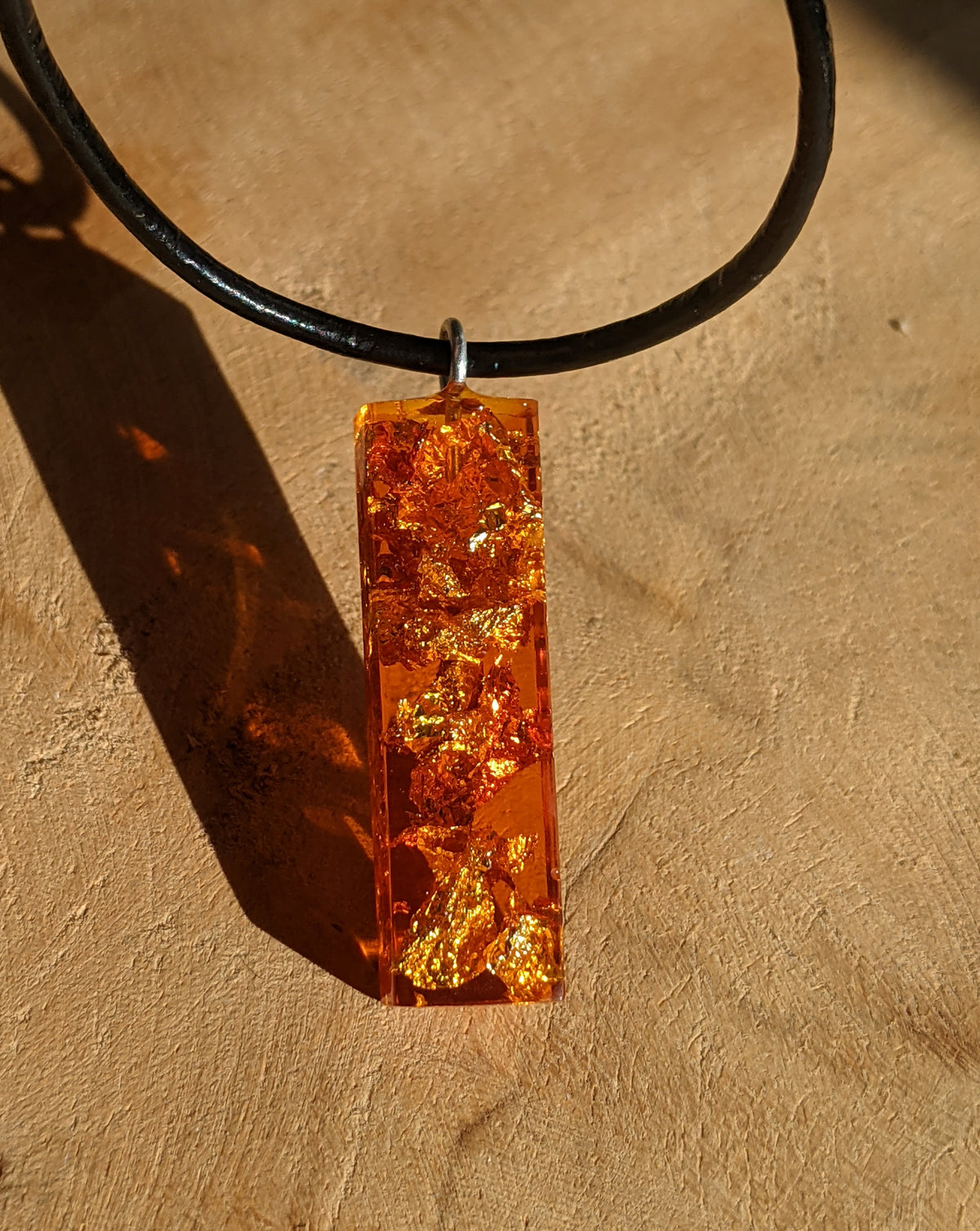 Close up view of gold and copper flakes inside amber resin necklace pendant EL-Creations