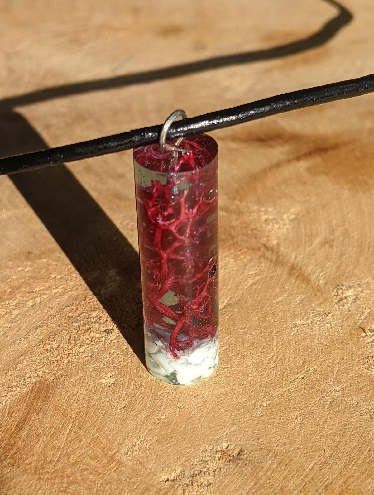 Close up view of teal green resin cylinder necklace with natural moss and white stone EL-Creations