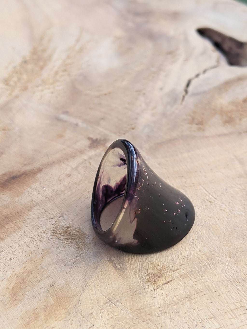 Purple ring with copper speckles on a wooden surface