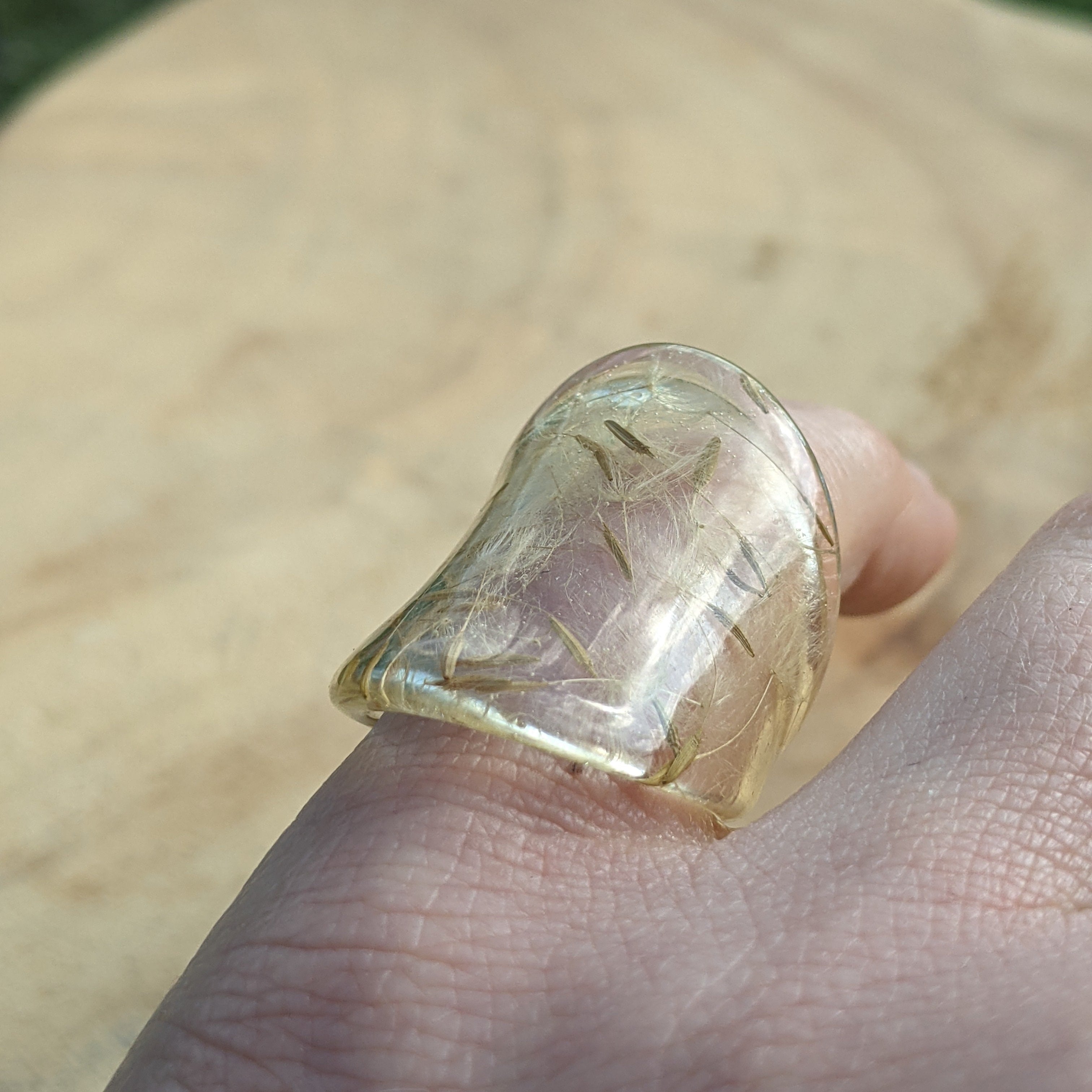 Clear gemstone ring on a finger with a blurred natural background