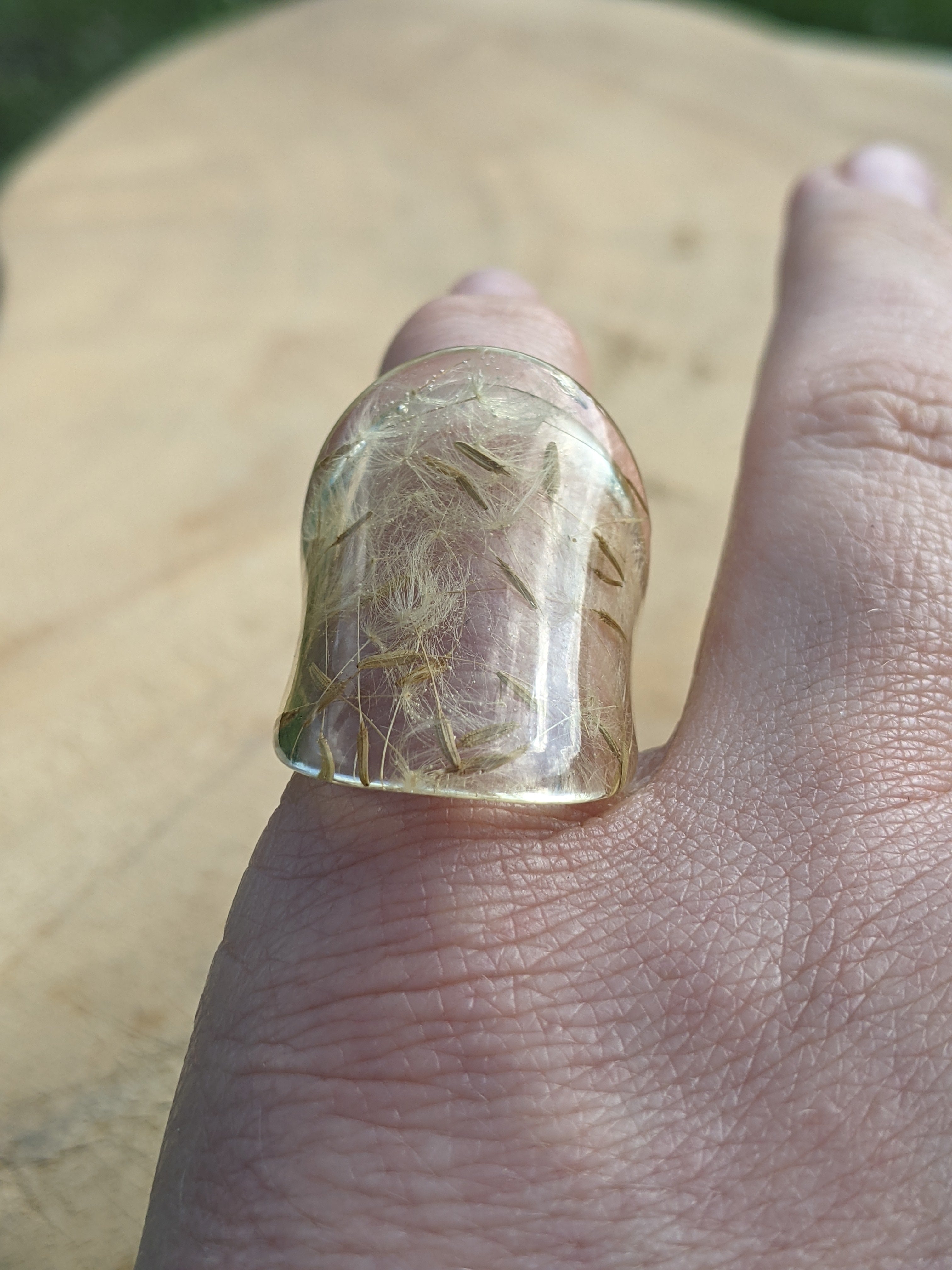 Ring with a clear stone on a finger against a blurred background