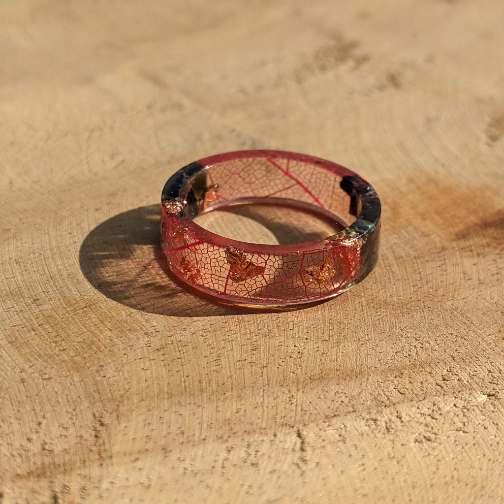 Red band ring with leaf pattern on a wooden surface