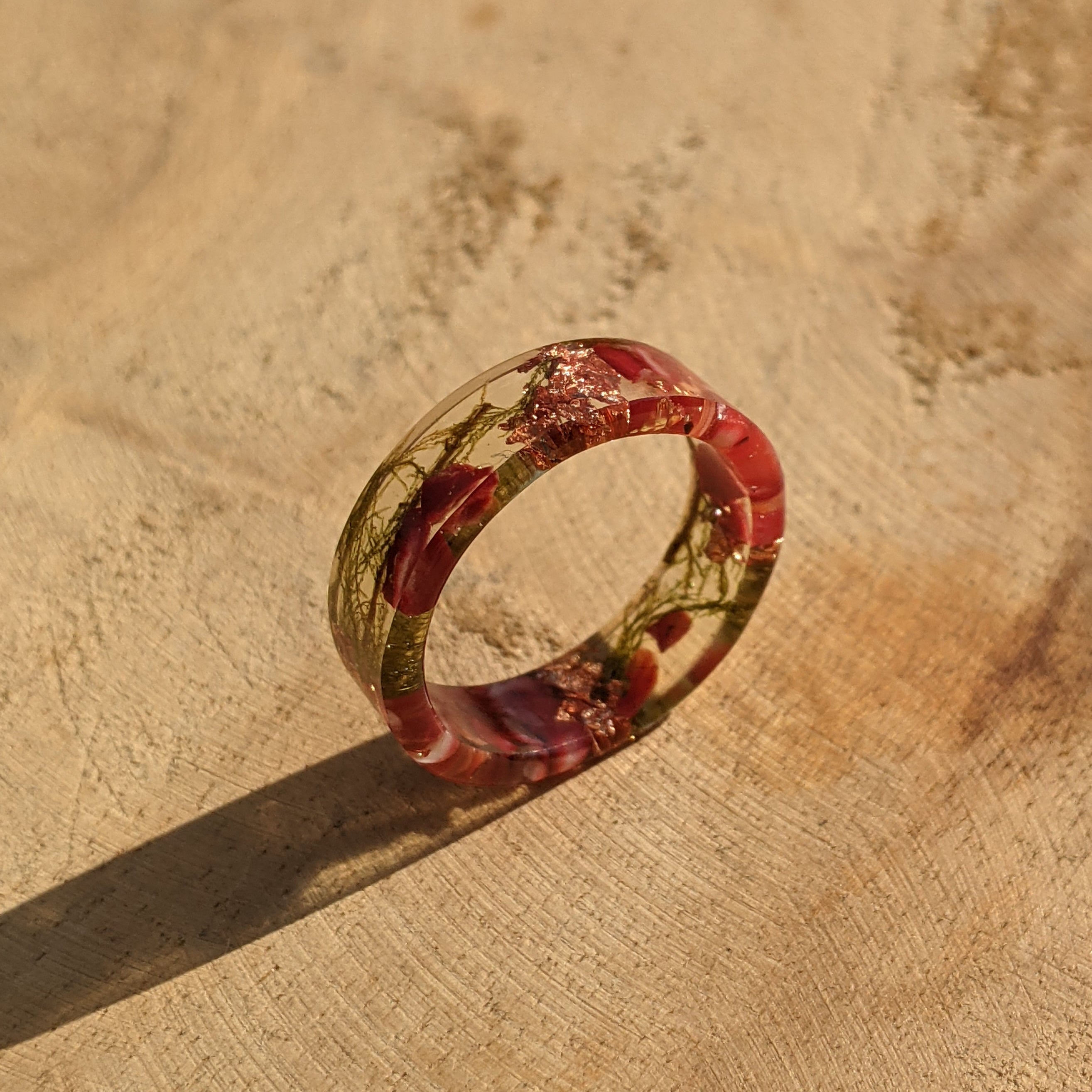 Ring with floral design on a textured beige surface