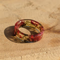 Resin ring with embedded materials on a textured beige surface
