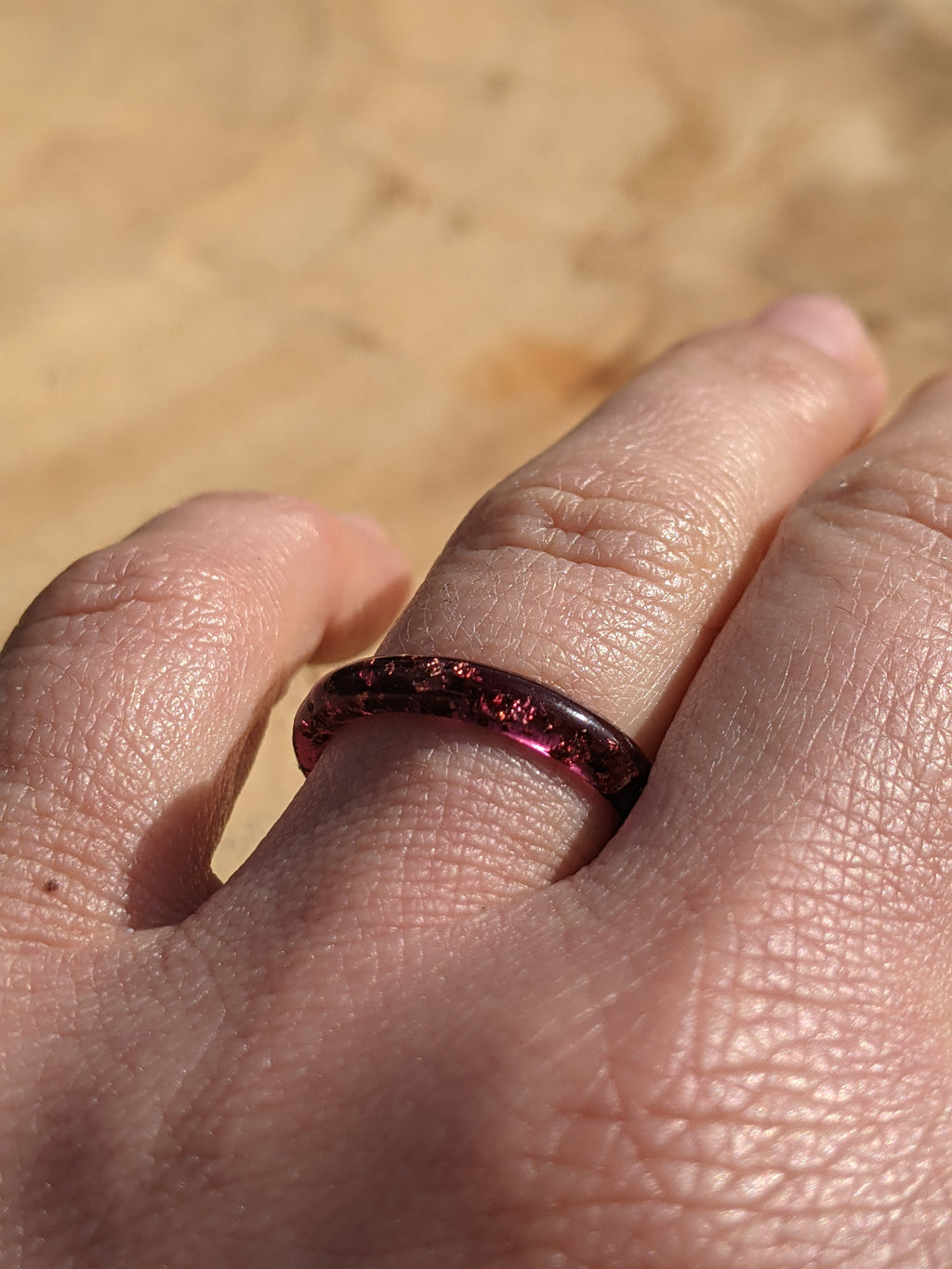 Close-up of a hand wearing a red ring with a blurred background