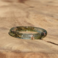 Greenish-brown thin ring on a wooden surface