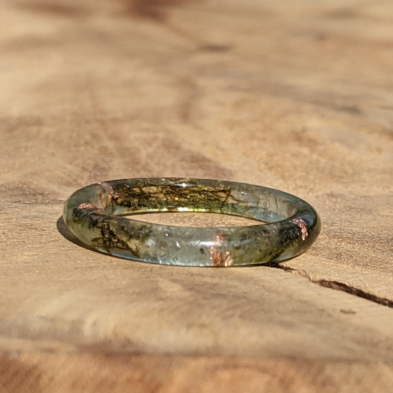 Greenish-brown thin ring on a wooden surface
