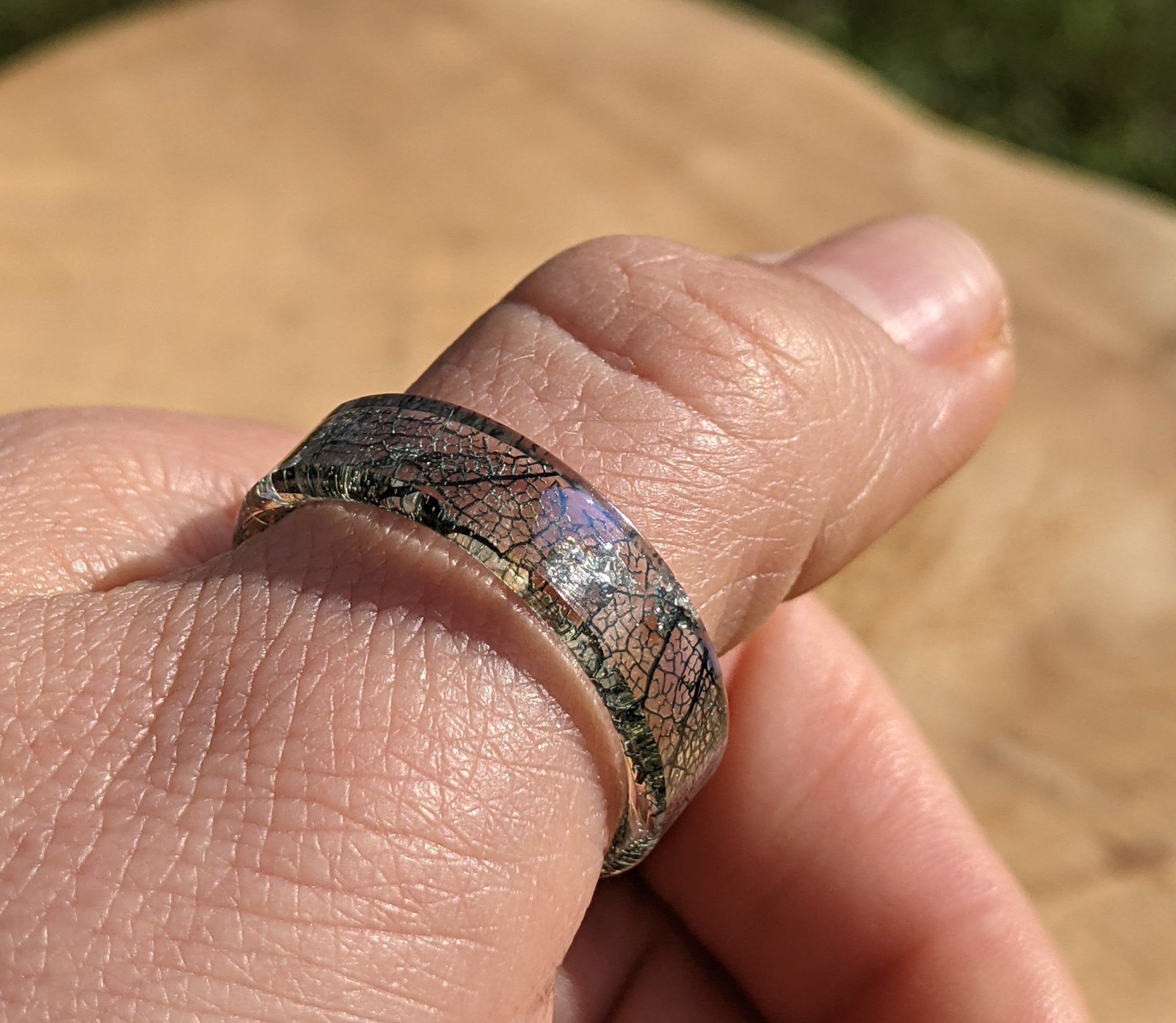 Close-up of a hand wearing a unique ring with a textured band.