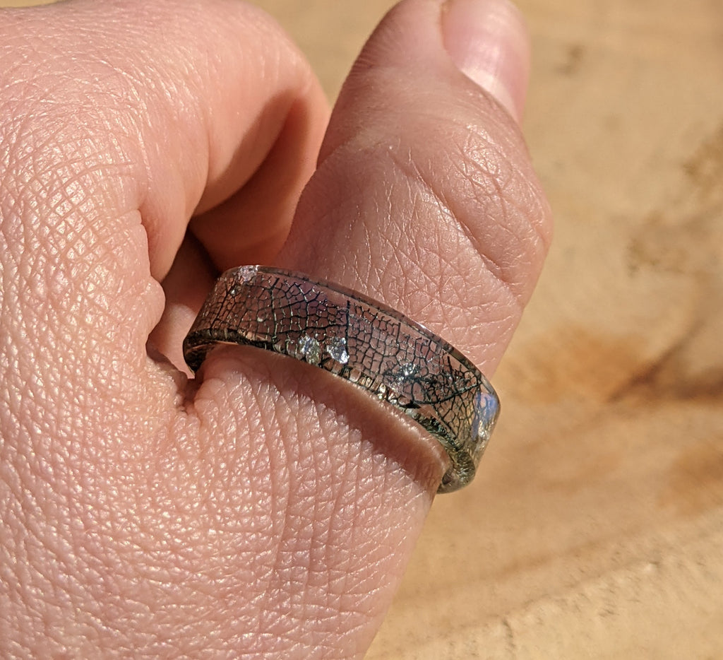 Close-up of a hand wearing a silver ring with a textured band.