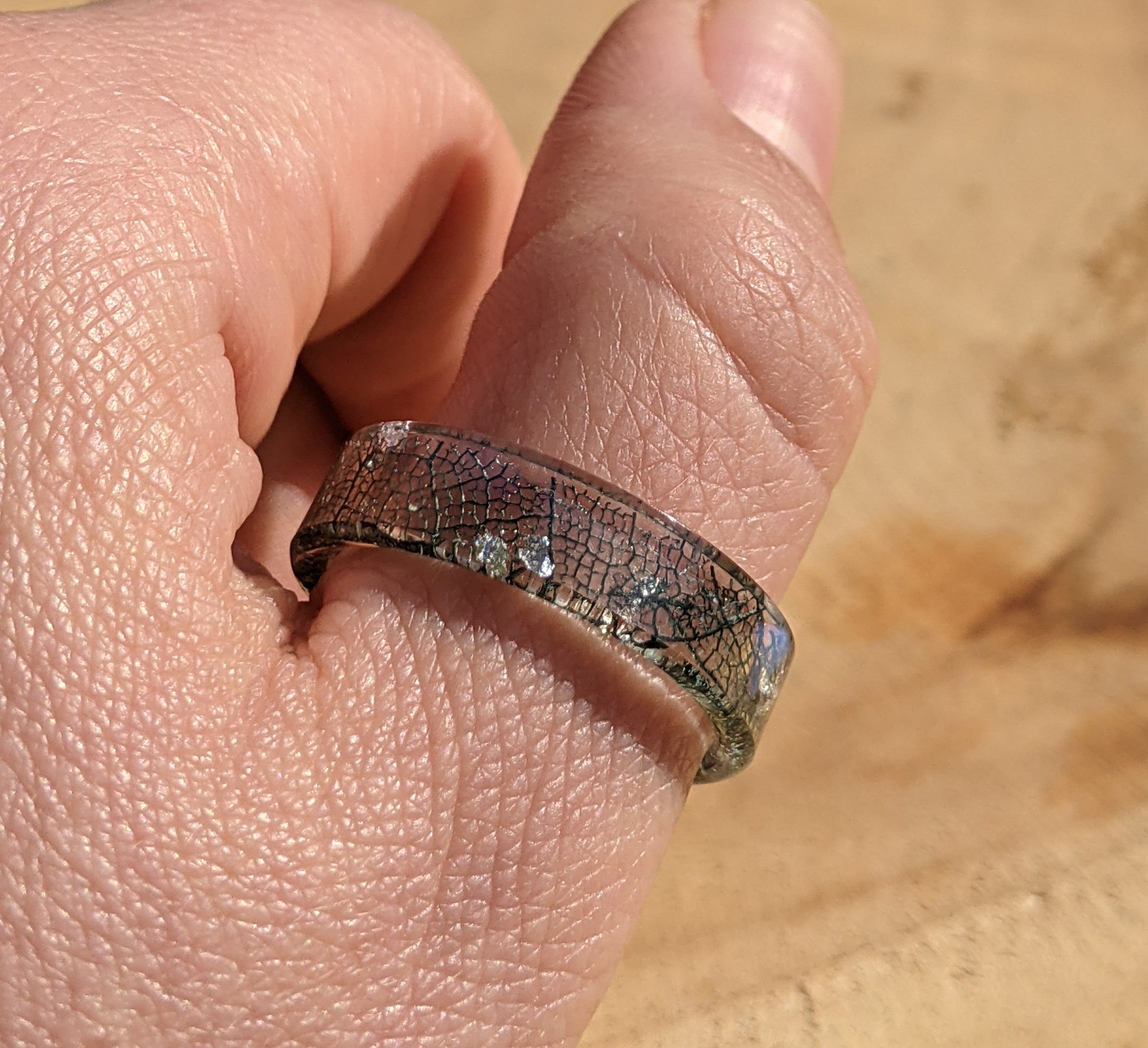 Close-up of a hand wearing a silver ring with a textured band.