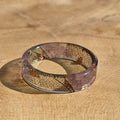 Glass band ring with leaf patterns on a wooden surface